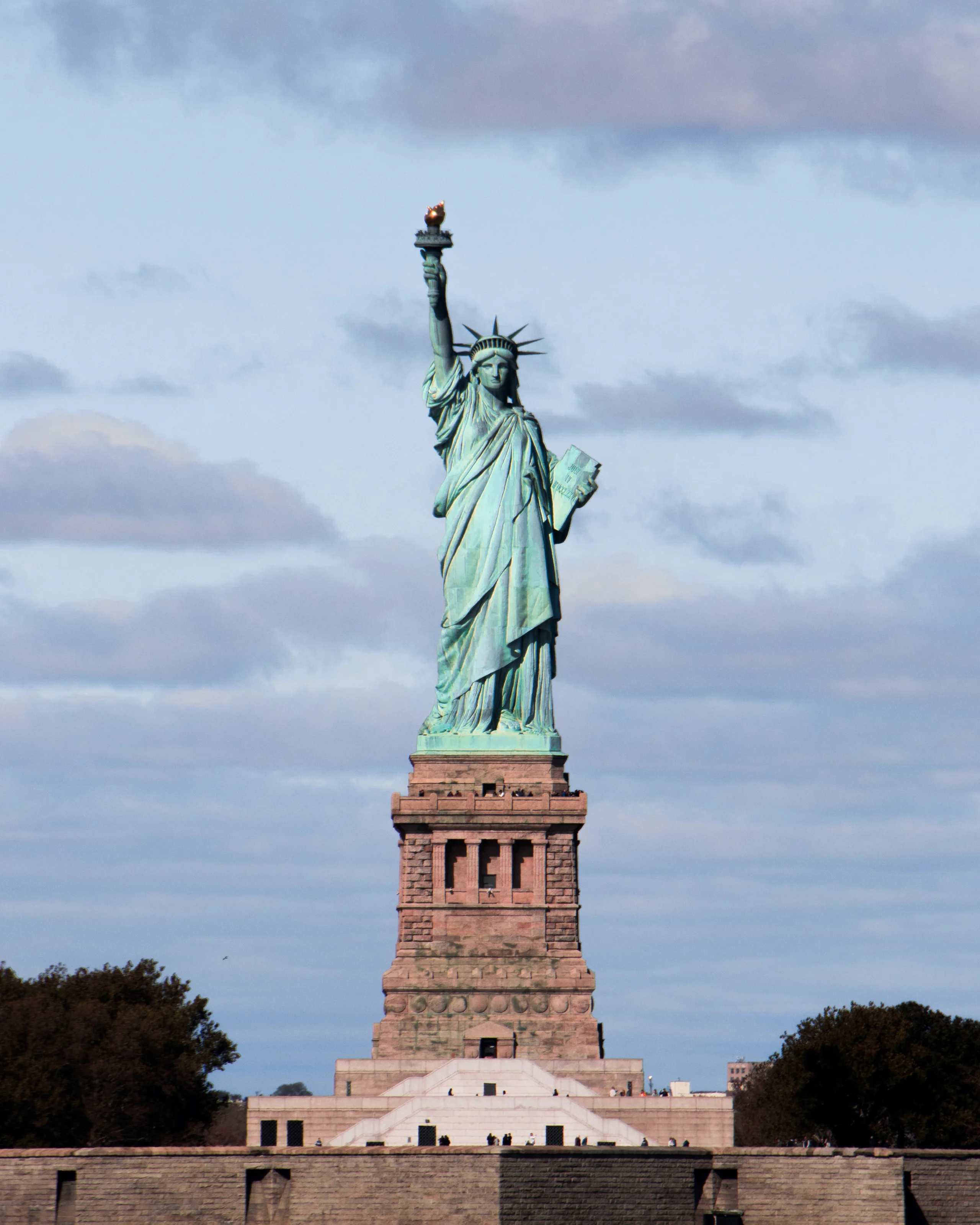 The Statue of Liberty on her pedestal under a soft blue sky
